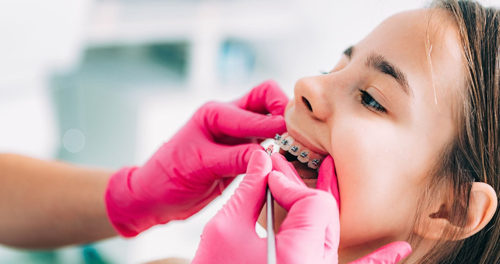 Person with teeth braces at the dentist's office, having their gums examined.