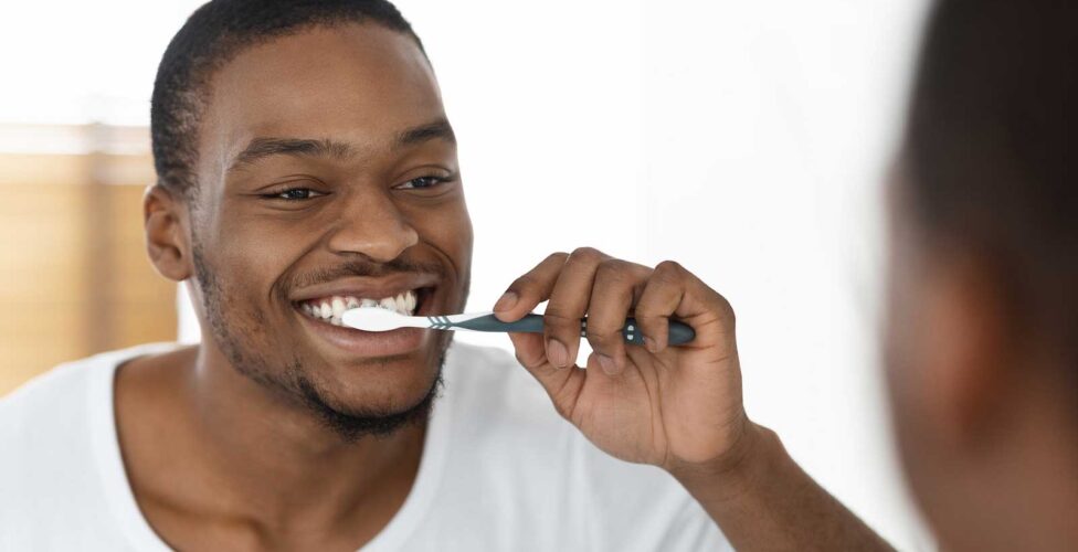 Man Brushing Teeth In Front Of A Mirror