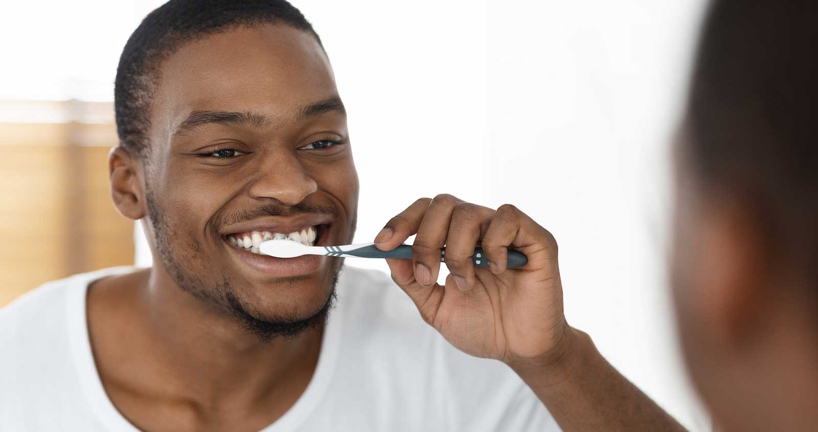 Man Brushing Teeth In Front Of A Mirror